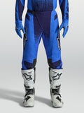 Alpinestars Techstar Swan, pantalones de motocross para hombre, azules con paneles perforados y botas blancas.