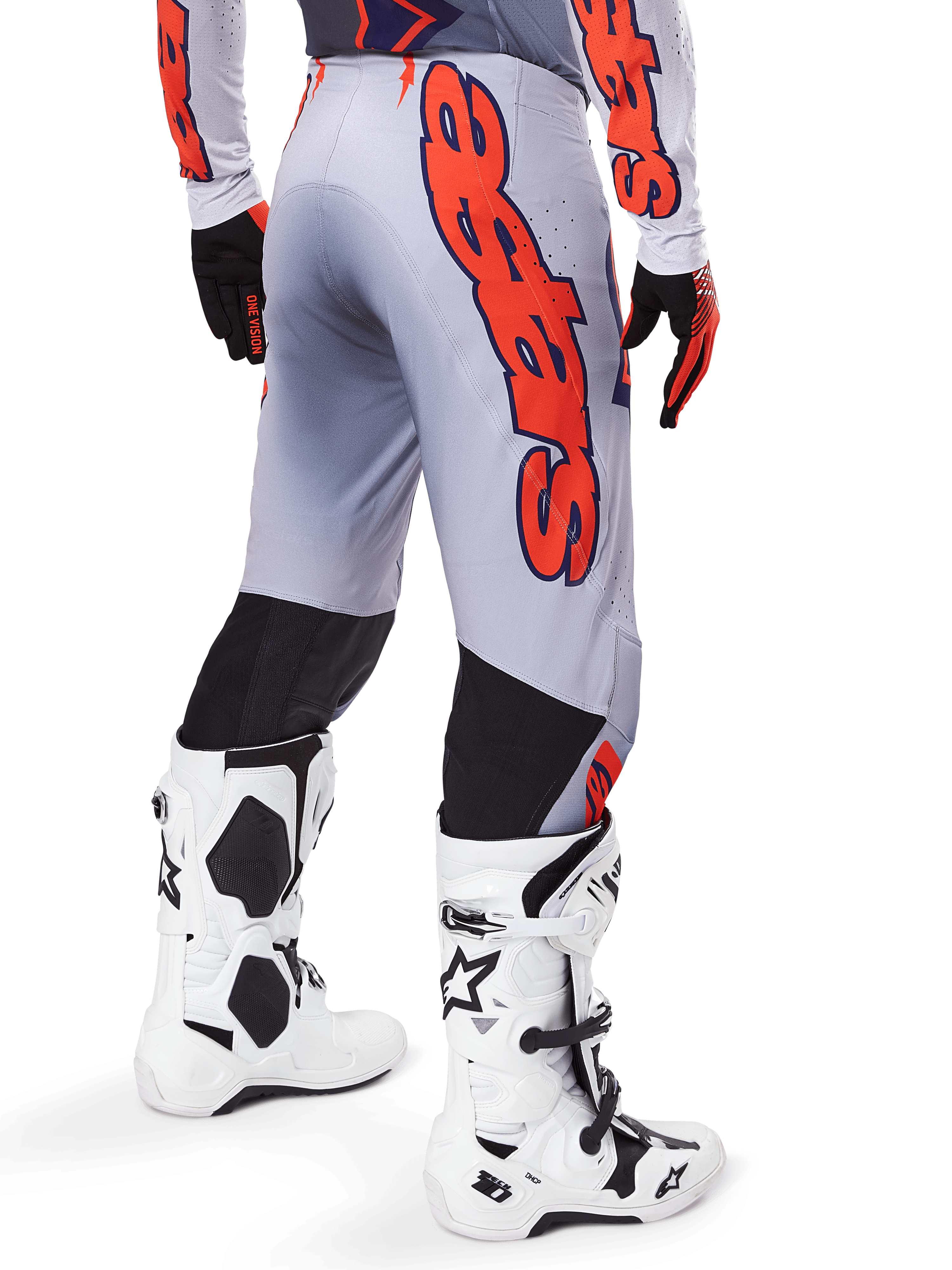 Alpinestars 2025 Supertech Lipan Pants, pantalones de motocross, gris y naranja flúor, vista trasera con un gran gráfico naranja de Alpinestars, paneles elásticos negros, usados con jersey a juego y botas blancas, equipamiento profesional de motocross