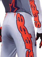 Alpinestars 2025 Supertech Lipan Jersey y Pantalones, conjunto de equipo de motocross, gris y naranja flúor, primer plano del lateral y la parte trasera con gran logotipo naranja de Alpinestars, tejido rip-stop de rendimiento con ventilación perforada