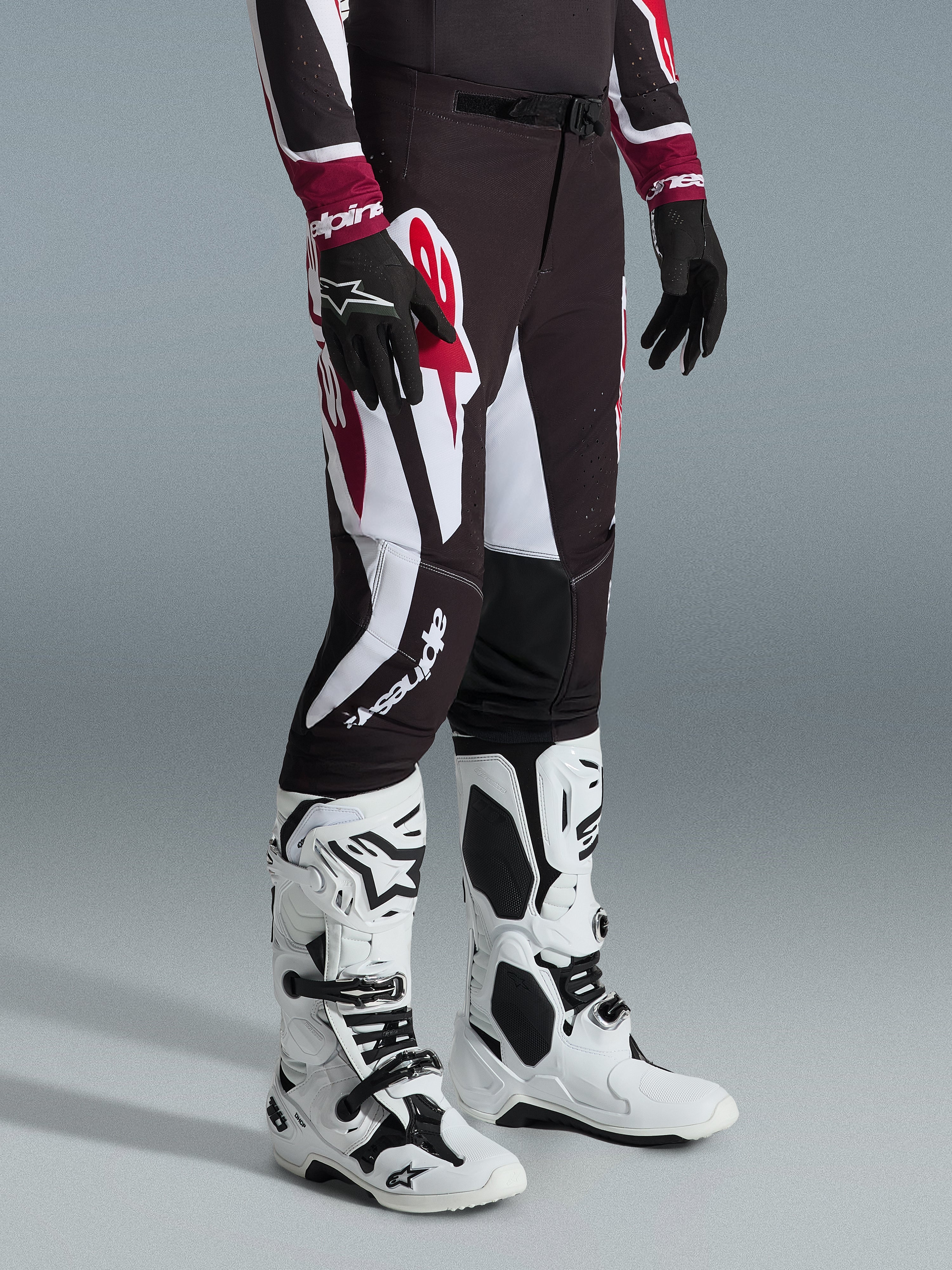 Pantalones Alpinestars Supertech AFD Vista 2026, pantalones de motocross en negro, rojo y blanco, usados con botas de motocross blancas y negras y guantes negros, con grandes patrones gráficos en blanco y rojo y diseño de ajuste atlético de competición
