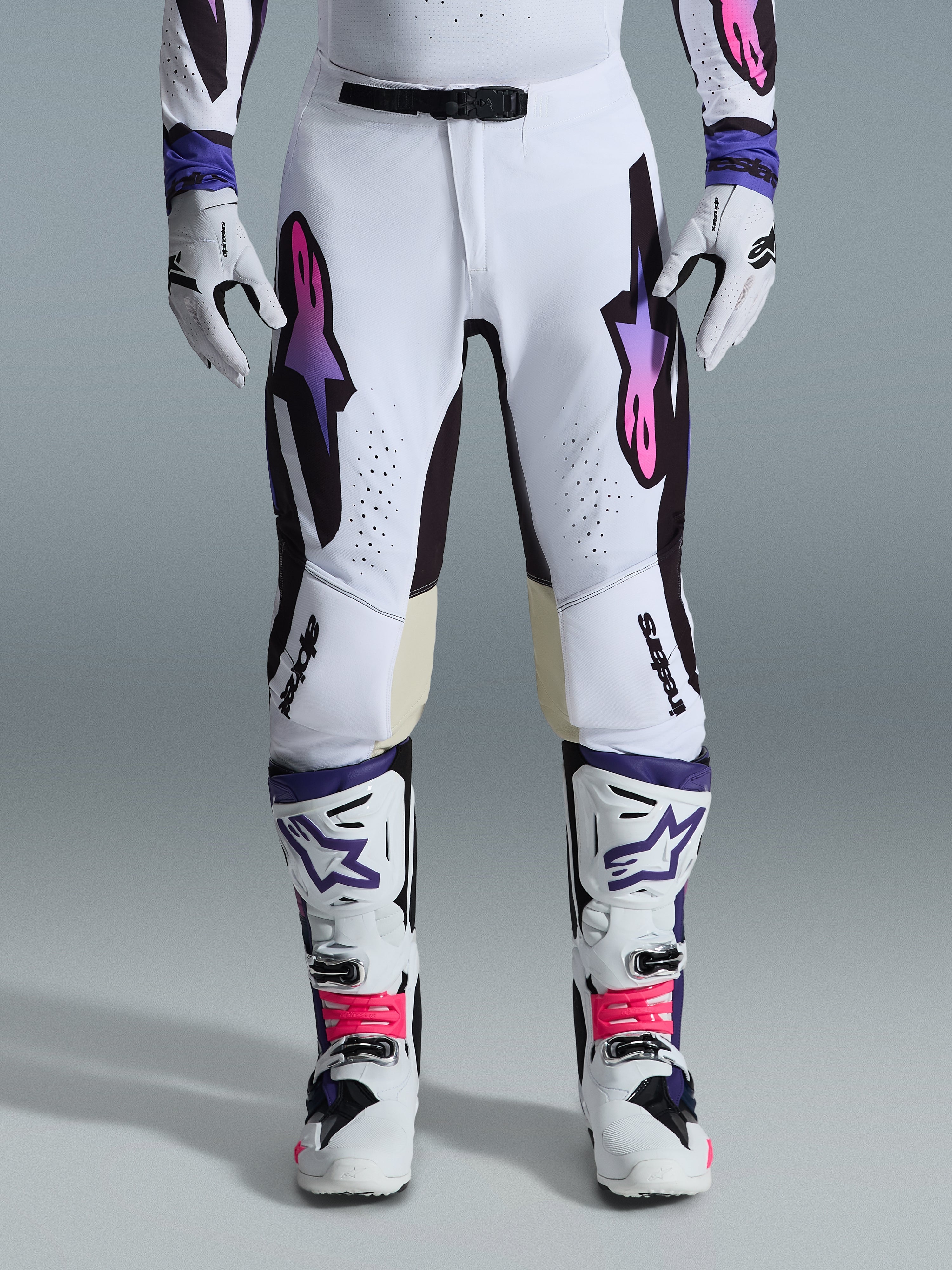 Alpinestars 2026 Supertech AFD Vista Gear Set, white motocross pants with purple and pink gradient logos, white boots with vibrant pink accents, white and black gloves, professional motocross racing outfit