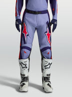 Alpinestars Pantalones Racer Air Hunt para motocross en color violeta y morado con detalles rosa flúor y botas blancas.