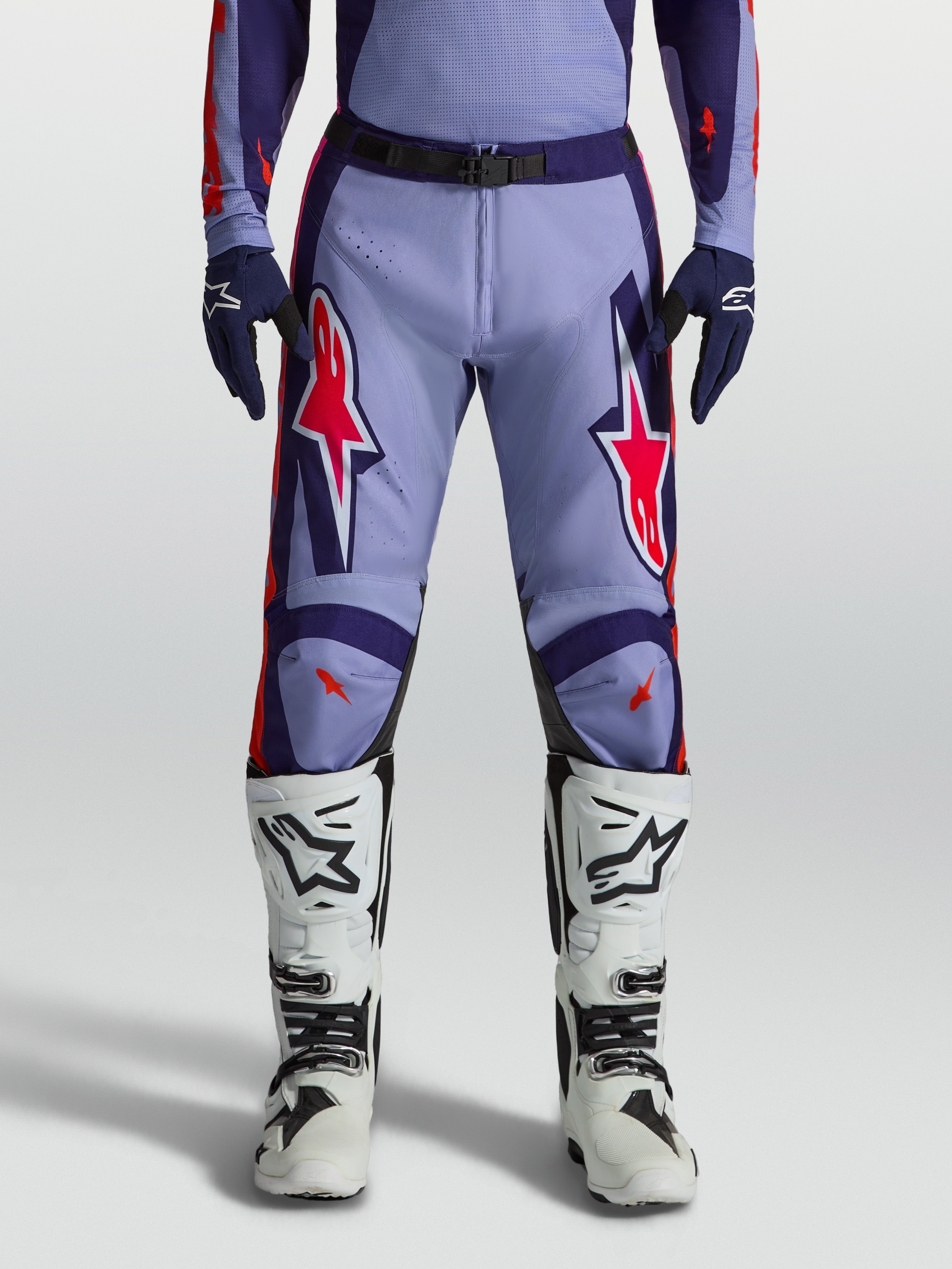 Alpinestars Pantalones Racer Air Hunt para motocross en color violeta y morado con detalles rosa flúor y botas blancas.