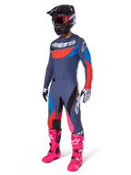 Alpinestars 2025 Techstar Dreem Pants, pantalones de motocross, gris multicolor con detalles en azul, rojo y rosa, usados con jersey a juego y botas rosa brillante, con casco negro y guantes blancos, conjunto completo de equipamiento para carreras todoterreno