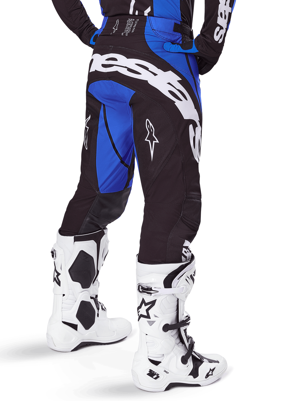 Pantalones Alpinestars Techstar Dreem 2025, pantalones de motocross para hombre, negros y azules, vista trasera con el llamativo logotipo blanco de Alpinestars en el asiento, combinados con botas de motocross blancas y negras y jersey azul a juego, ajuste atlético para competición off-road