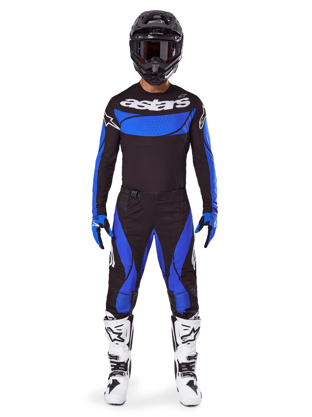Piloto de motocross con el conjunto de equipo Alpinestars 2025 Techstar Dreem, camiseta negra con panel azul en el pecho y mangas, pantalones negros y azules a juego, casco negro con gafas y botas blancas, conjunto de motocross coordinado para carreras todoterreno.