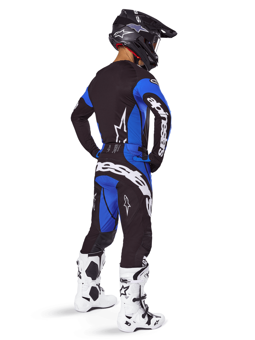 Alpinestars Techstar Dreem Pants 2025, pantalones de motocross negros y azules, usados por un piloto con equipamiento completo incluyendo jersey a juego, casco negro y botas blancas, con un llamativo logo blanco en la parte trasera y un ajuste de competición de alto rendimiento.