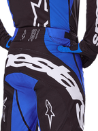 Alpinestars 2025 Techstar Dreem Pants, pantalones de motocross, negro y azul, vista trasera que muestra el llamativo logotipo blanco en el asiento, detalles en azul y detalle de la cintura Techstar, combinados con camiseta y guantes a juego