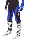 Alpinestars 2025 Techstar Dreem Pants, pantalones de motocross, negros y azules, usados con botas de motocross blancas y guantes azules, con el logo de Alpinestars en blanco en la pierna, construcción duradera para carreras off-road