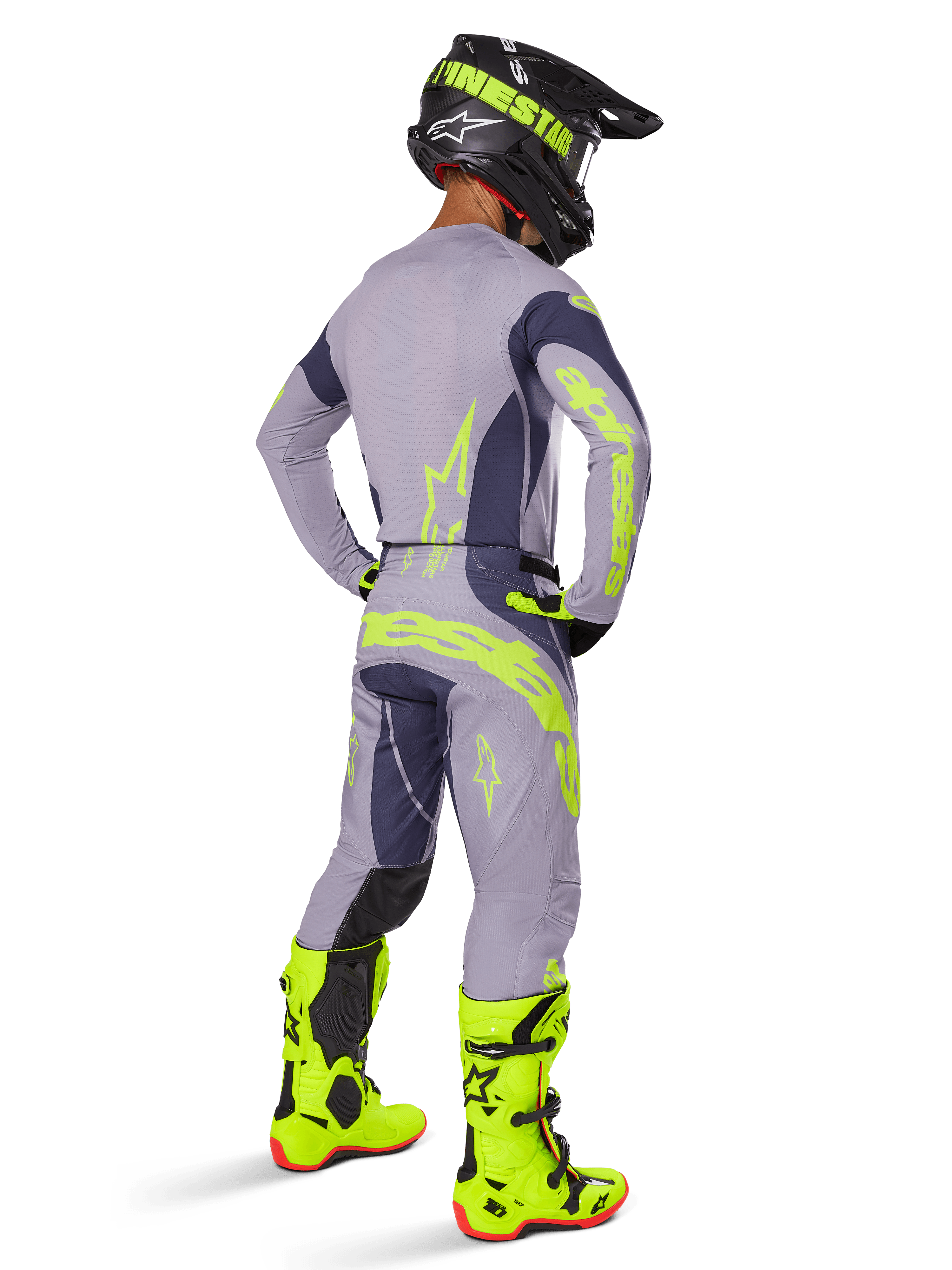 Motocross rider seen from behind wearing full racing gear, including Alpinestars 2025 Techstar Dreem Pants in Gray and Dark Gray with bold neon yellow accents, matching gray jersey with neon graphics, bright neon yellow boots, and black helmet, coordinated professional motocross outfit