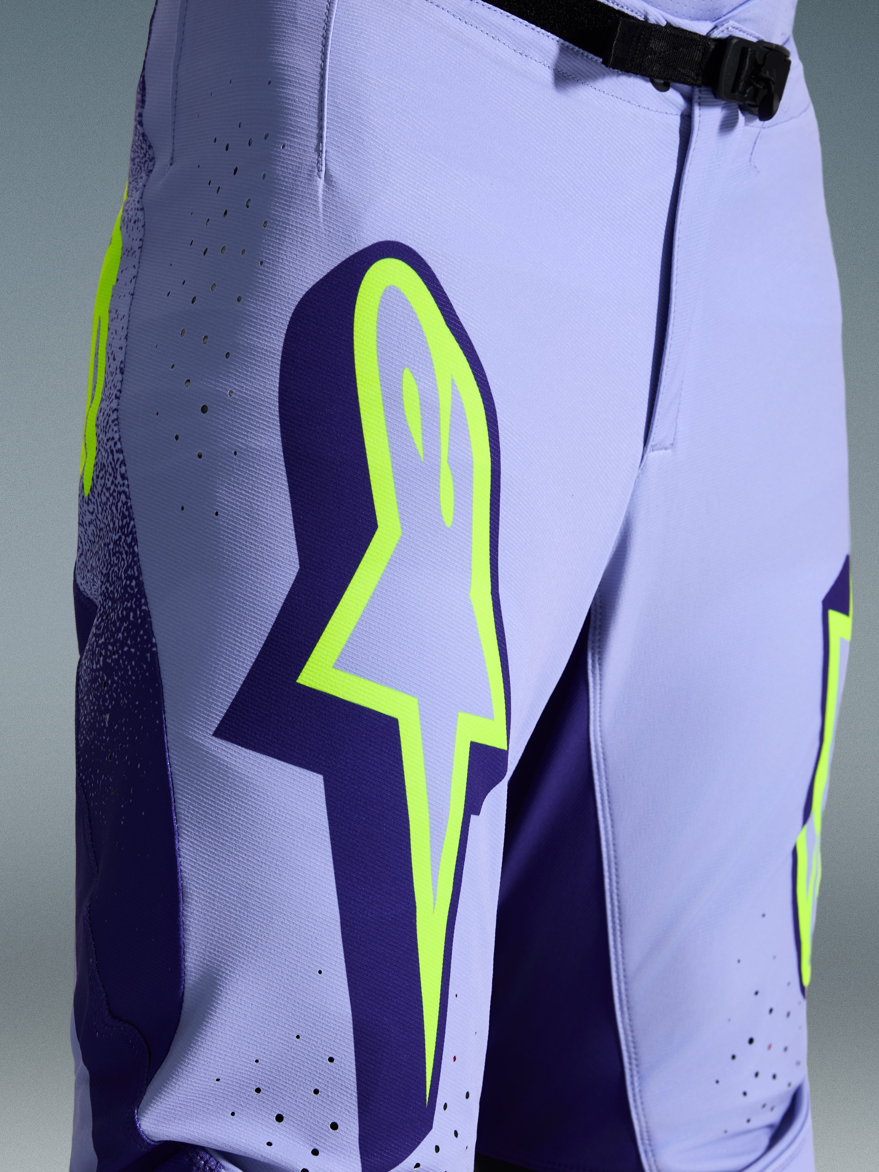Alpinestars 2026 Supertech Scenz Pants, Motocross Pants, Purple Yellow Fluo, close-up featuring large yellow logo on the thigh, laser-cut perforations for ventilation, and magnetic waist buckle, athletic-fit off-road gear