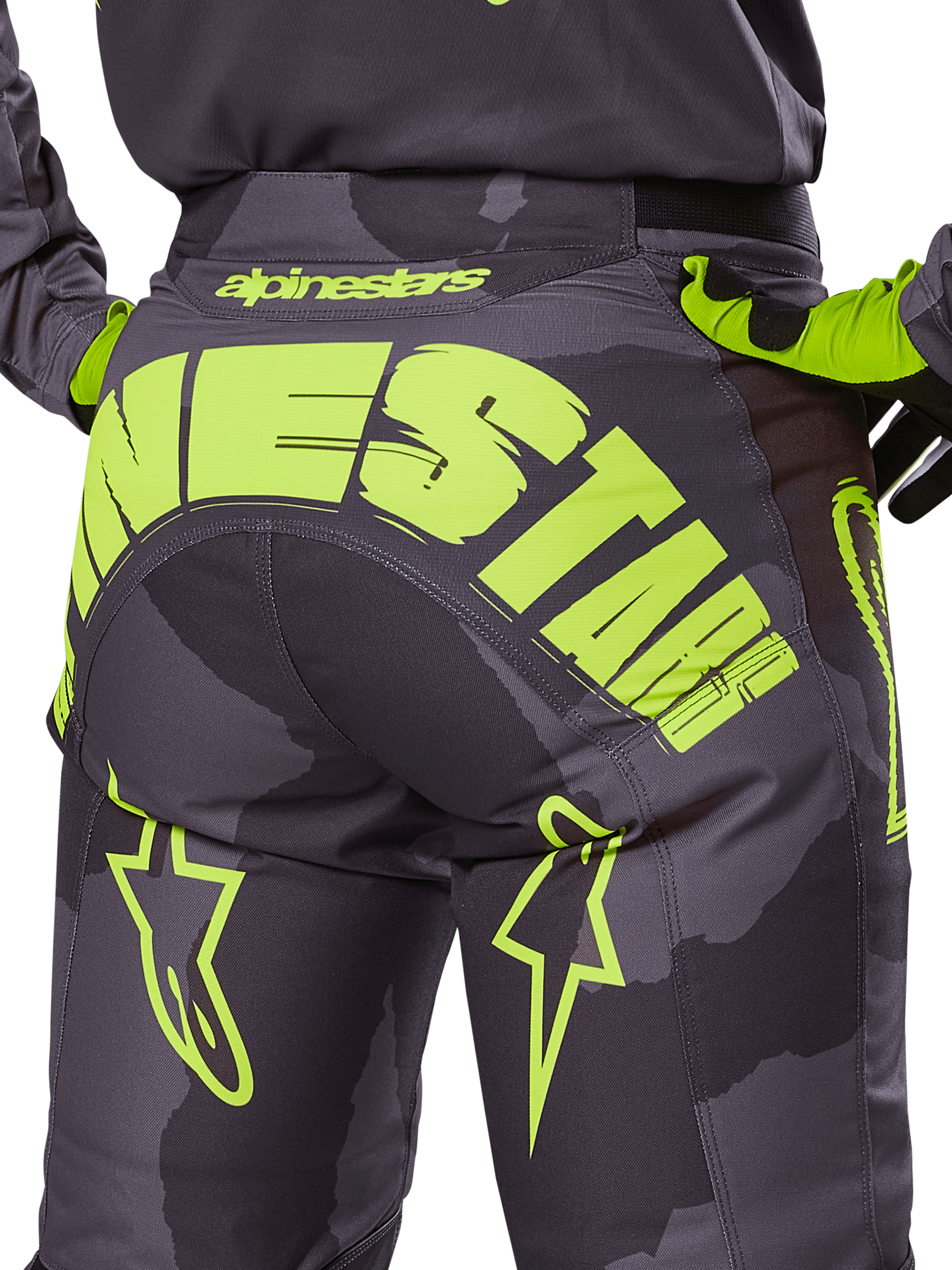 Alpinestars Racer Hollow Pants 2025, pantalones de motocross, camuflaje oscuro y amarillo flúor, con un gran logotipo de Alpinestars en amarillo en la parte trasera, patrón de camuflaje táctico con detalles en amarillo vibrante y construcción duradera para carreras off-road.