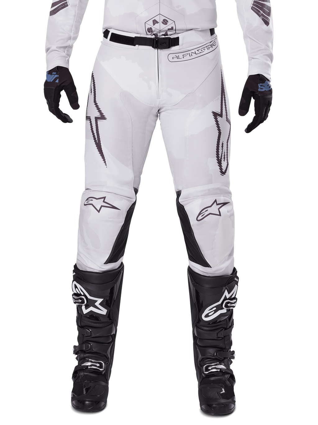 Alpinestars 2025 Racer Hollow Pants, pantalones de motocross, marrón camuflaje claro, usados con guantes negros y botas de motocross, con un sutil patrón de camuflaje, gráficos negros y logotipos Astars, diseño ergonómico para conducción off-road