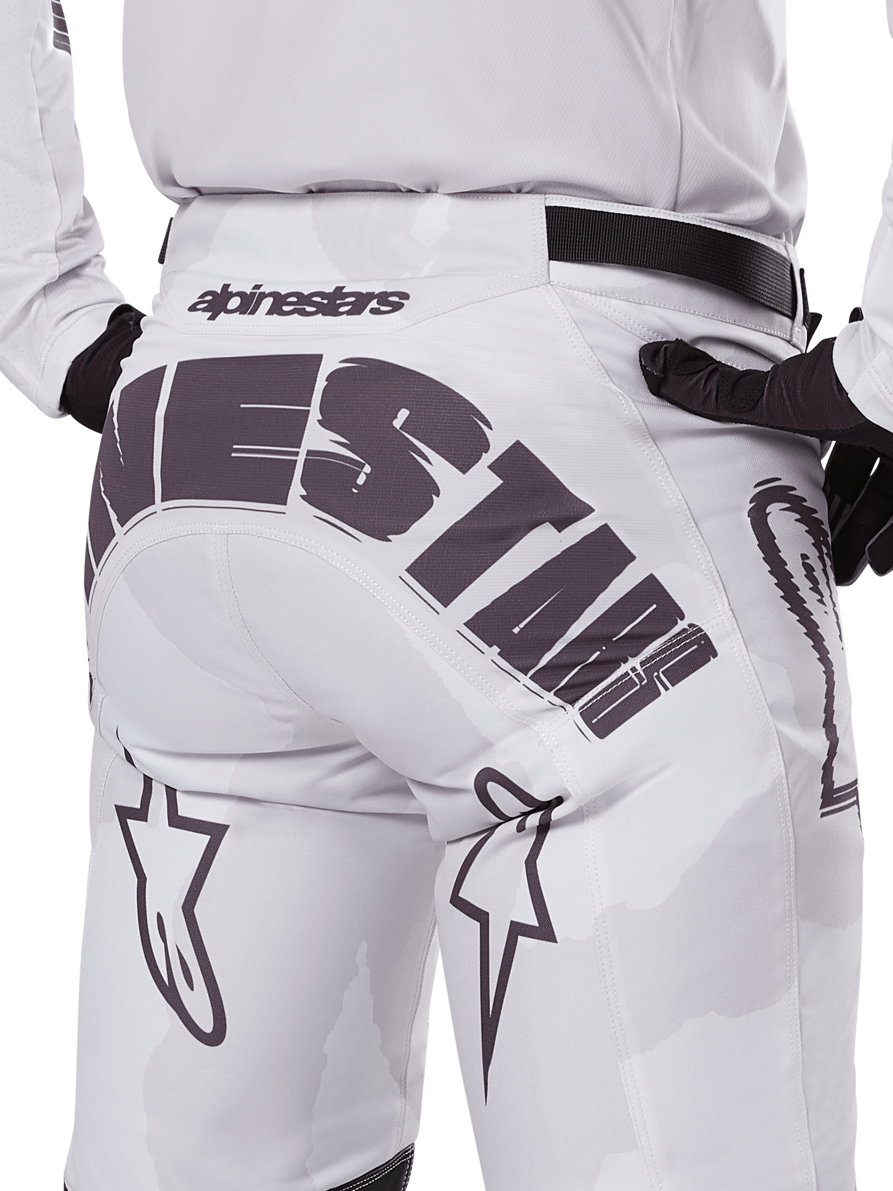 Alpinestars 2025 Racer Hollow Pants, pantalones de motocross, marrón camuflaje claro, vista trasera de cerca con un gran logotipo de Alpinestars en la parte posterior, logos de estrella en las piernas y una correa de cintura ajustable negra, diseñados para carreras off-road