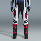 Alpinestars 2026 Techstar Knif Gear Set, equipamiento de motocross, pantalones negros y blancos con logotipos de estrellas rojas grandes, usados con botas de carreras negras y rojas y guantes negros, ajuste atlético profesional para rendimiento todoterreno