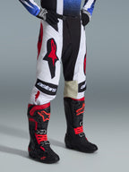 Alpinestars 2026 Techstar Knif Gear Set, pantalones y botas de motocross, blanco, negro y rojo, con logotipos destacados y construcción multimaterial, usado con guantes negros, kit de competición profesional para rendimiento todoterreno.