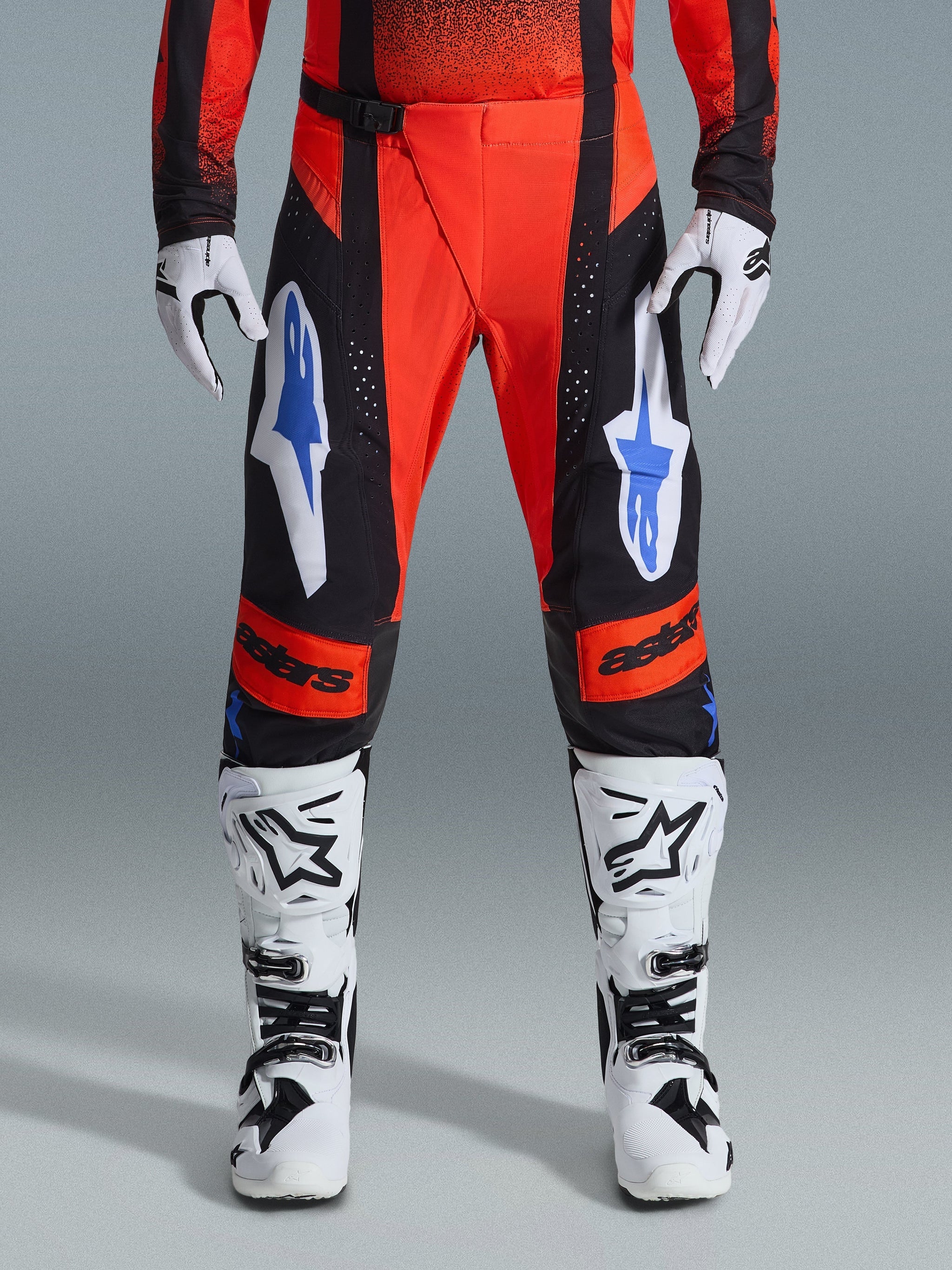 Alpinestars 2026 Techstar Knif Pants, Motocross Pants, Orange, Black, and UCLA Blue, worn with matching jersey, white and black motocross boots, and gloves, featuring bold branding on the thighs and knees, athletic race fit for off-road racing