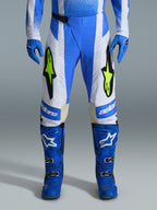 Alpinestars 2026 Techstar Knif Pants, pantalones de motocross, azul UCLA, negro y amarillo flúor, usados con guantes y botas azules a juego, con paneles blancos y logotipos amarillo flúor vibrantes, ajuste ergonómico de competición para rendimiento todoterreno