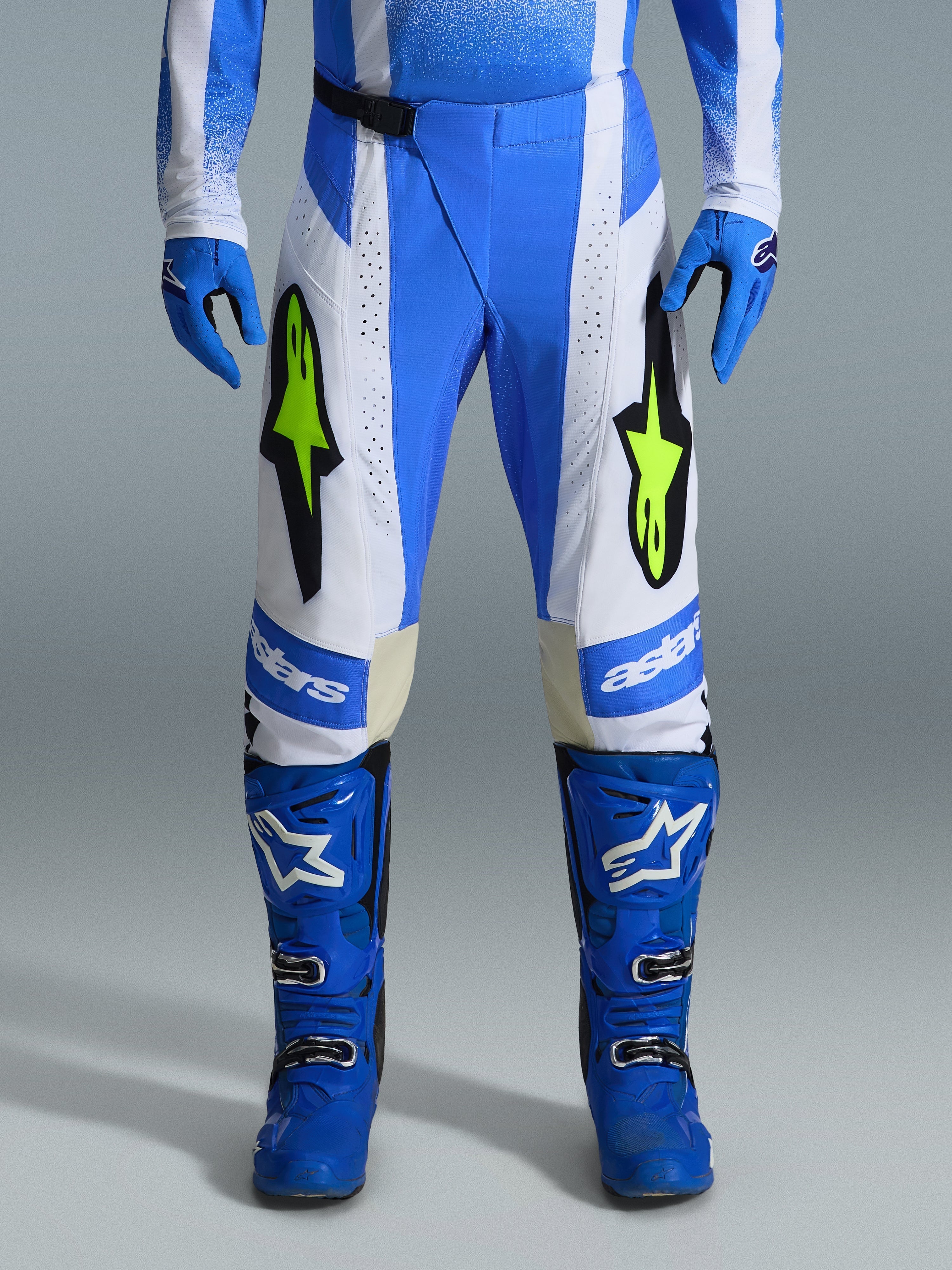 Alpinestars 2026 Techstar Knif Pants, pantalones de motocross, azul UCLA, negro y amarillo flúor, usados con guantes y botas azules a juego, con paneles blancos y logotipos amarillo flúor vibrantes, ajuste ergonómico de competición para rendimiento todoterreno