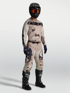 Alpinestars Racer Lone, conjunto de motocross en camuflaje arena y marrón con casco y botas negras para off-road.