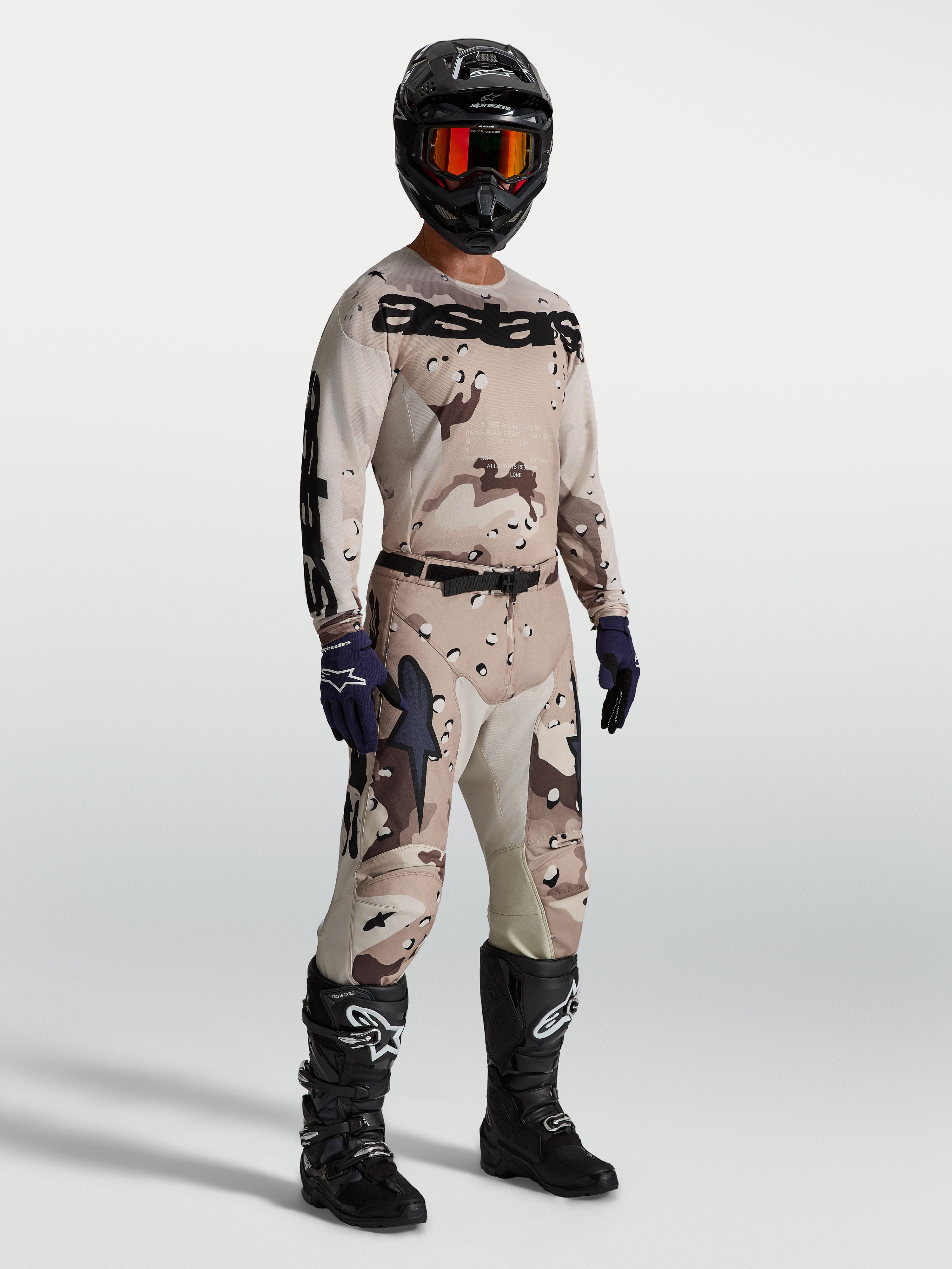 Alpinestars Racer Lone, conjunto de motocross en camuflaje arena y marrón con casco y botas negras para off-road.