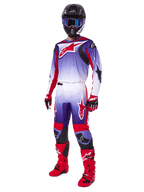 Piloto de motocross con equipamiento completo de carreras, pantalones Fluid Wurx 2025 y jersey a juego en morado, rojo brillante y blanco, logotipo grande de Alpinestars en rojo, botas y guantes rojos, casco negro con gafas azules, conjunto coordinado para carreras off-road