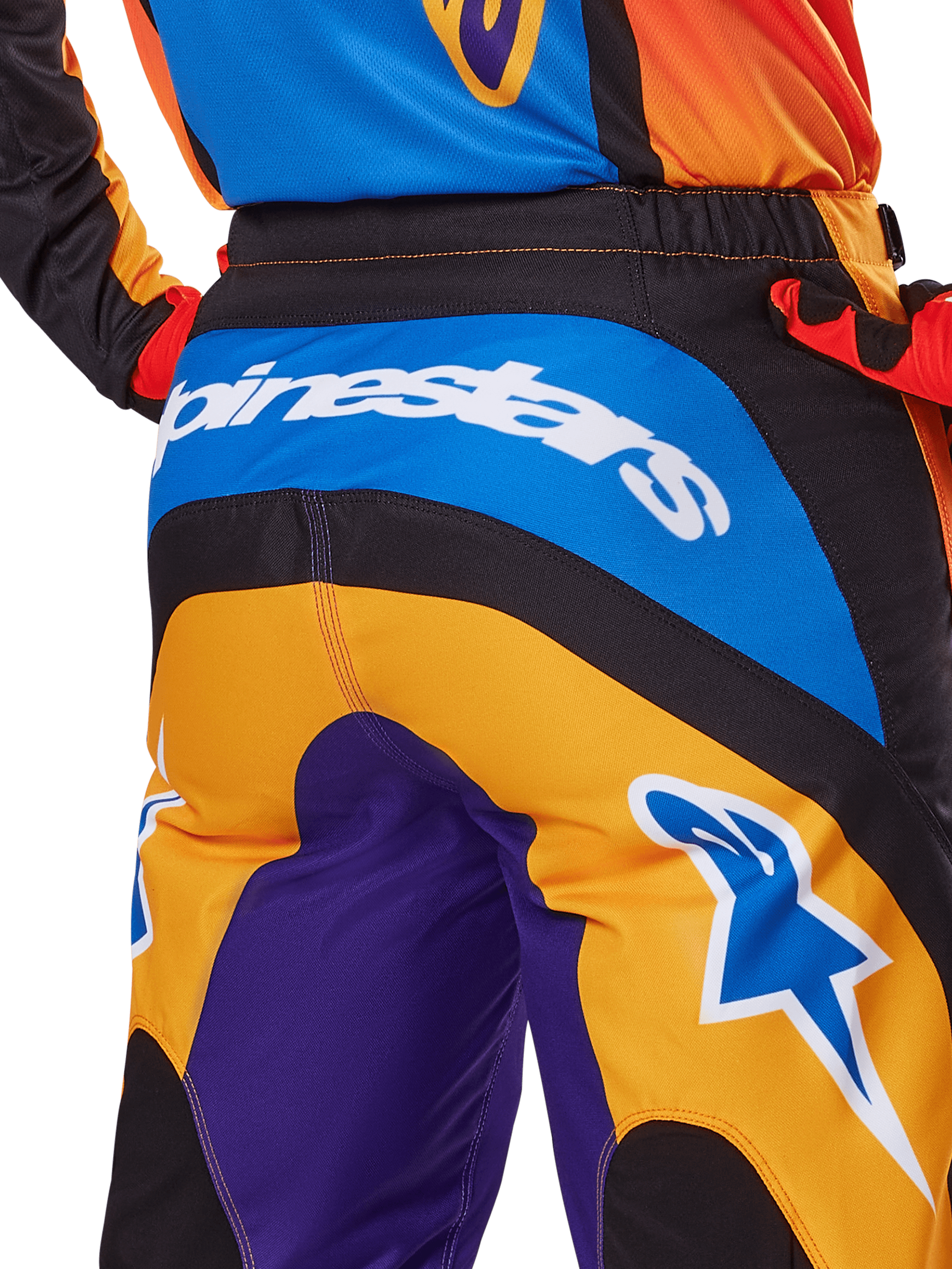 Alpinestars 2025 Fluid Wurx Pants, pantalones de motocross, vista trasera en naranja, azul y morado, con un logotipo blanco de Alpinestars en el asiento y un logotipo Astar azul en la pierna, construcción técnica para conducción todoterreno