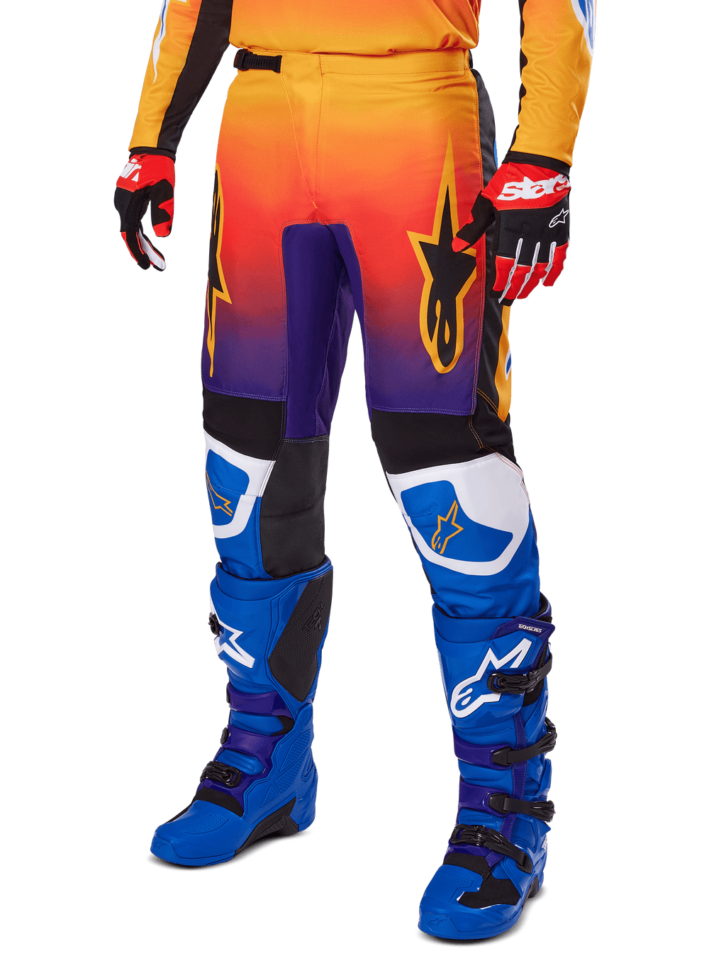 Alpinestars 2025 Fluid Wurx Pants, pantalones de motocross, degradado multicolor en naranja, rojo y púrpura con paneles negros y azules, usados con botas azules y guantes rojos, con gráficos del logo de estrella y detalles blancos en las rodillas, equipamiento de alto rendimiento para carreras todoterreno
