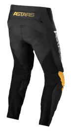 Alpinestars Techstar Quadro Pants, pantalones de motocross, negro, amarillo y mandarina, vista trasera con la marca 'ASTARS' en amarillo en la cintura, inserciones de malla negra para ventilación y paneles ergonómicos en las rodillas en amarillo y mandarina para durabilidad en carreras off-road