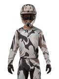 Alpinestars 2024 Racer Tactical Jersey, Motocross Jersey, Iron Camo Dust Gray camouflage pattern, rider wearing matching helmet and goggles with black gloves, technical gear for off-road racing