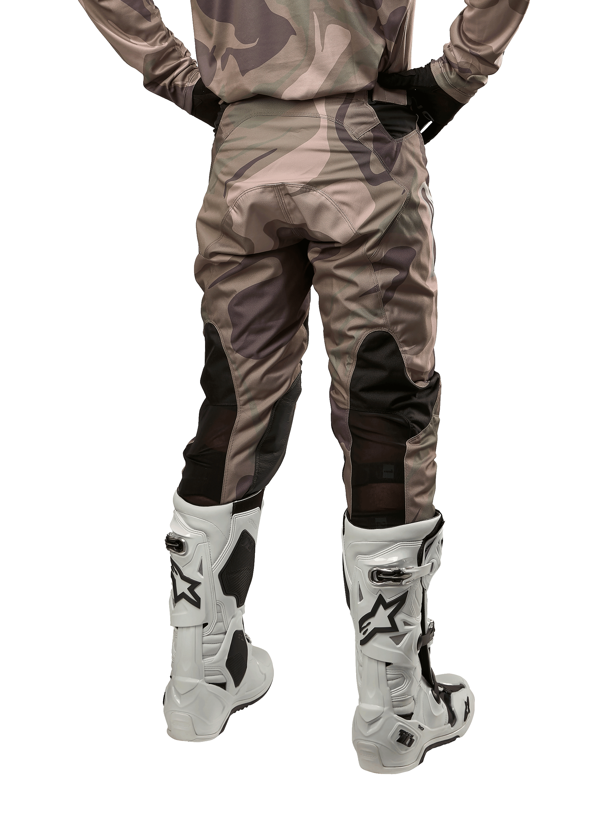 Alpinestars 2024 Racer Tactical Pants, pantalones de motocross, camuflaje verde militar y marrón, vista trasera que muestra el patrón de camuflaje y paneles elásticos transpirables negros en la parte inferior de las piernas, usados con botas de motocross blancas, equipo técnico duradero para conducción todoterreno