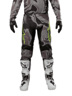 Alpinestars 2024 Racer Tactical Pants, pantalones de motocross, Cast Gray Camo Magnet, combinados con jersey de camuflaje a juego, guantes negros y botas blancas y negras, con logos de estrella verde lima en los muslos y paneles elásticos negros, vista frontal de equipamiento para conducción off-road