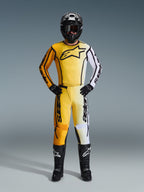 Alpinestars 2026 Fluid Apex Pants, pantalones de motocross en amarillo, negro y blanco, usados como un conjunto de carreras completo con jersey degradado a juego, casco negro y botas, equipamiento profesional para conducción off-road
