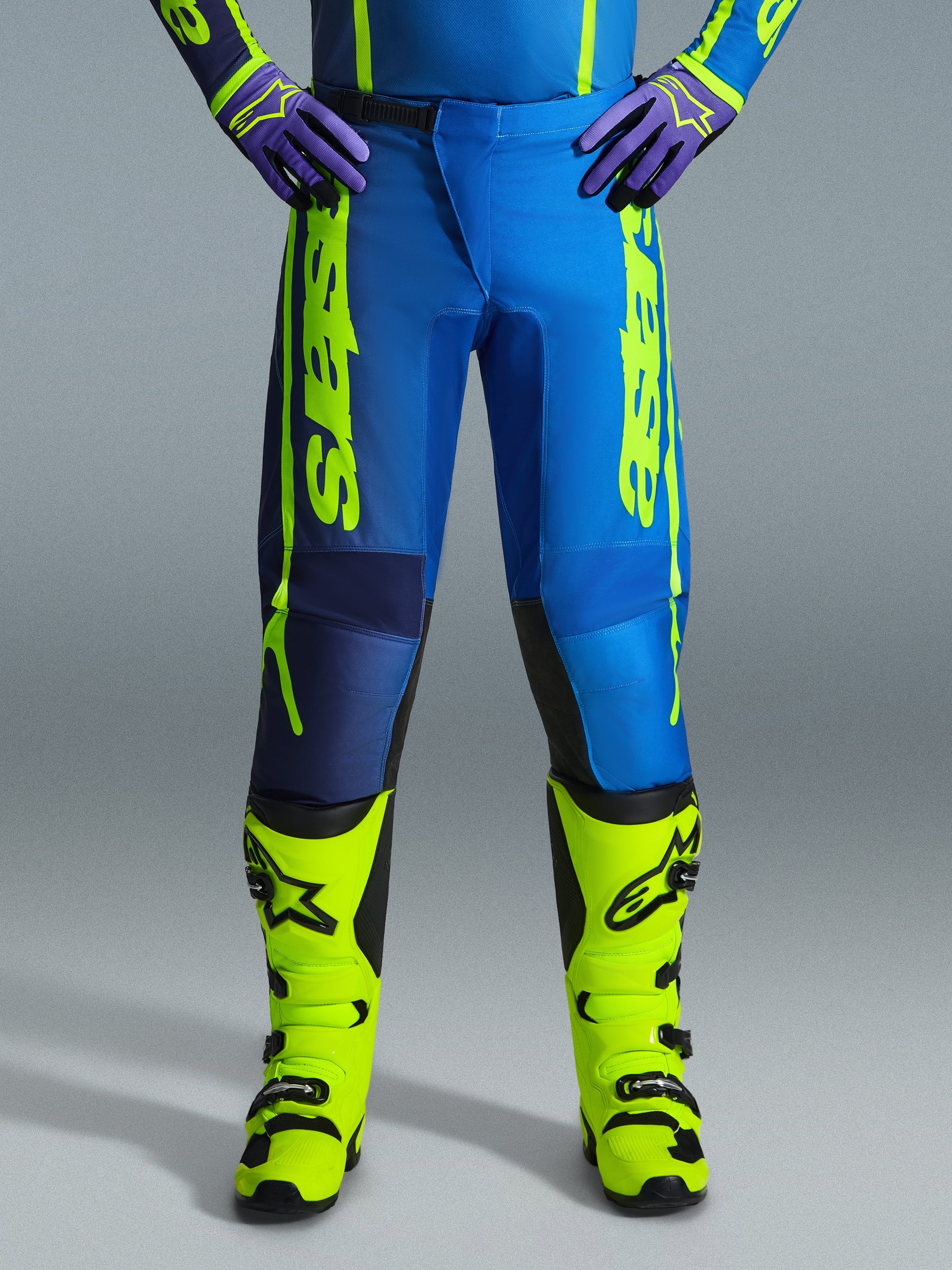 Pantalones Alpinestars 2026 Fluid Apex, pantalones de motocross, azul y amarillo fluo, combinados con botas amarillo fluo a juego y guantes morados, marca llamativa en amarillo en los laterales, diseño ergonómico para competición off-road