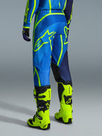 Alpinestars 2026 Fluid Apex Pants, pantalones de motocross, azul y amarillo flúor, vista trasera del piloto con equipamiento a juego y botas amarillo flúor, con logotipos llamativos de Alpinestars y diseño ergonómico