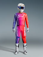 Piloto de motocross con pantalones Fluid Apex 2026 y jersey a juego, degradado de púrpura y naranja, casco blanco con gafas, botas y guantes blancos, equipamiento de carreras Alpinestars coordinado para rendimiento off-road.