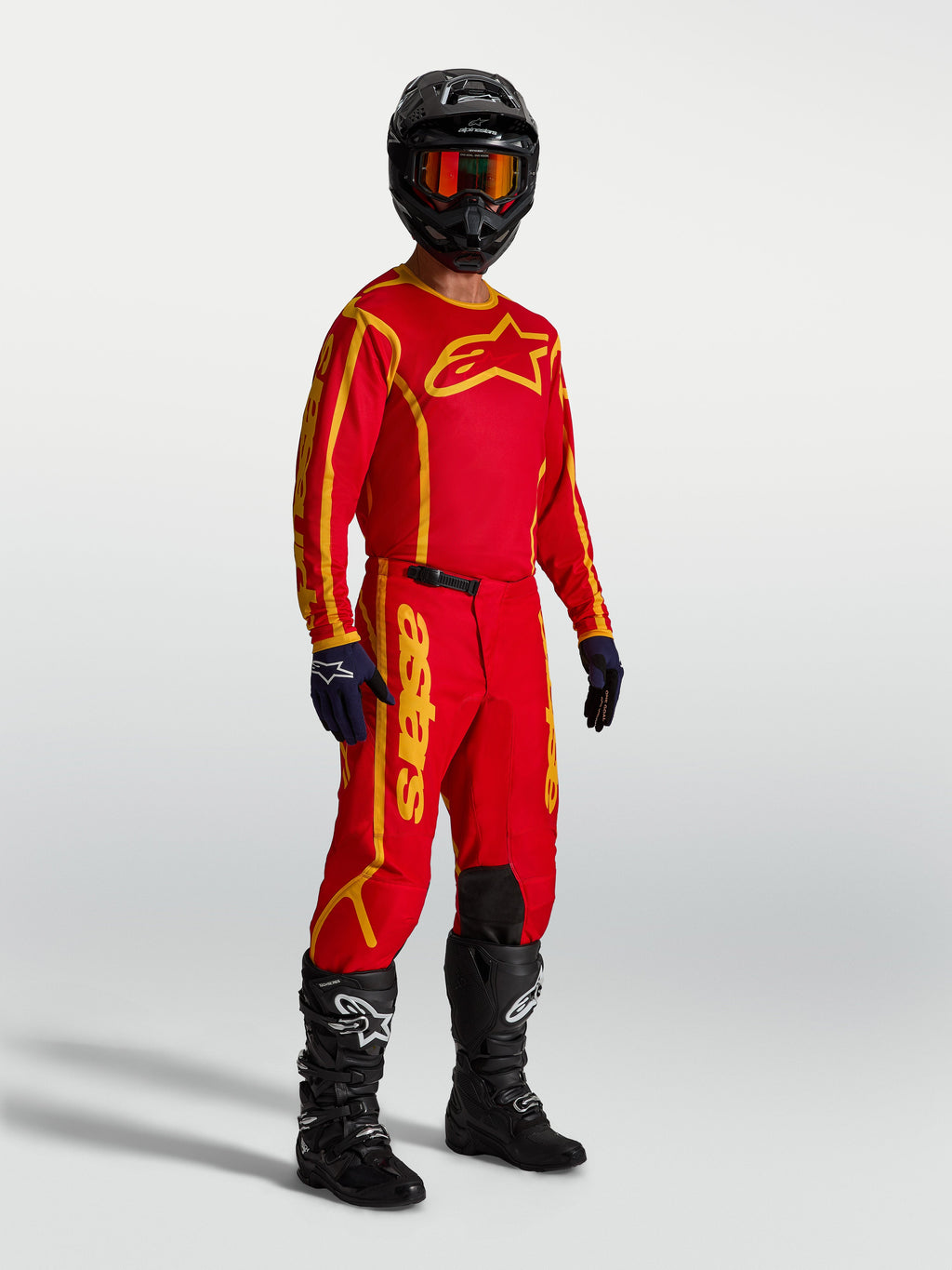 Alpinestars Fluid Apex V2, pantalones de motocross para hombre, rojos y dorados, equipamiento de alto rendimiento para todoterreno mostrado en modelo con jersey y botas