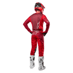 Pantalones Alpinestars Racer Hoen 2024 y jersey a juego en Mars Red Burgundy, vista trasera de un piloto de motocross con equipamiento completo que incluye casco rojo y botas blancas, destacando el ajuste atlético y la marca para carreras fuera de carretera