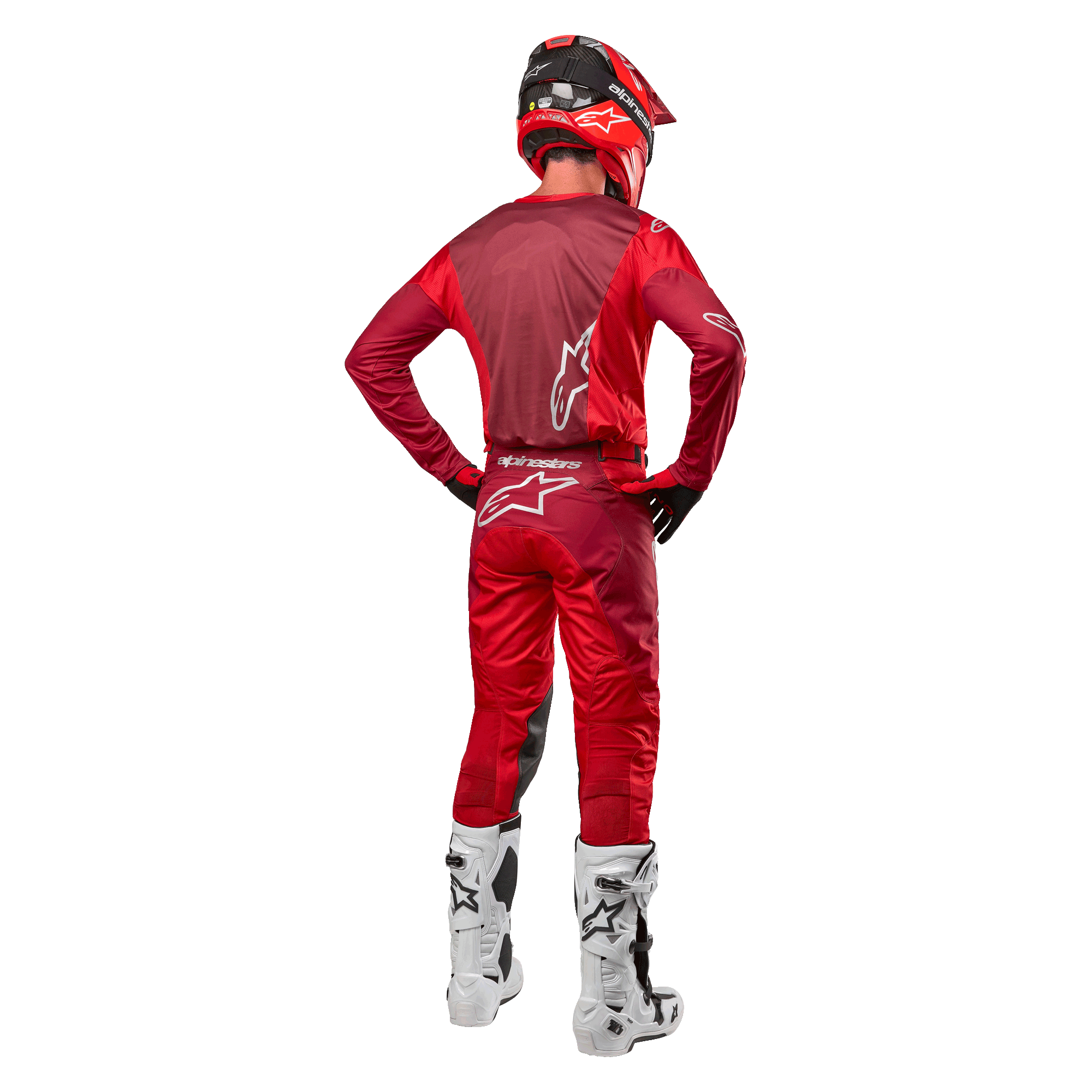 Pantalones Alpinestars Racer Hoen 2024 y jersey a juego en Mars Red Burgundy, vista trasera de un piloto de motocross con equipamiento completo que incluye casco rojo y botas blancas, destacando el ajuste atlético y la marca para carreras fuera de carretera