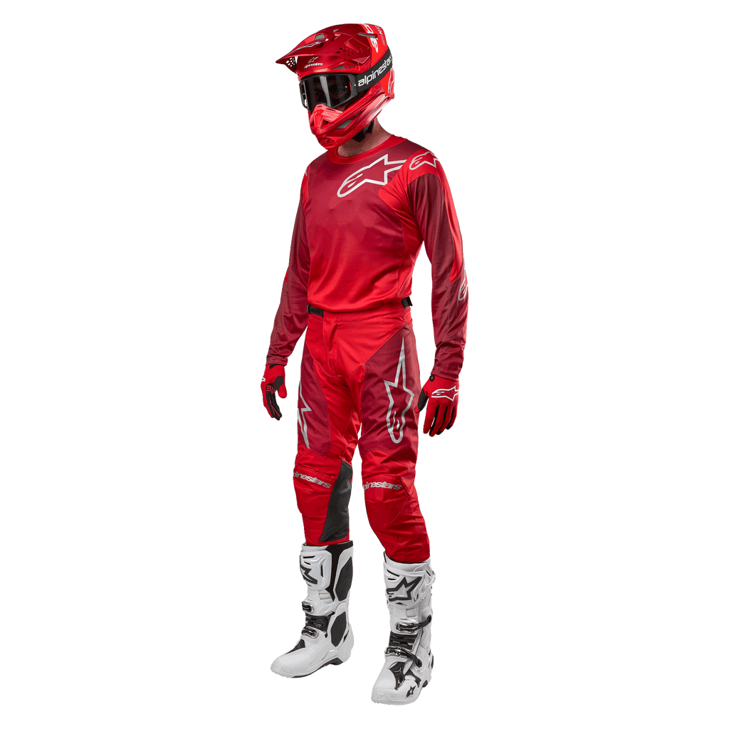 Piloto de motocross con equipamiento completo de competición, pantalones y jersey Alpinestars 2024 Racer Hoen en Mars Red Burgundy, casco rojo, guantes rojos y botas blancas y negras, conjunto coordinado para carreras fuera de carretera