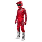 Piloto de motocross con equipamiento completo de competición, pantalones y jersey Alpinestars 2024 Racer Hoen en Mars Red Burgundy, casco rojo, guantes rojos y botas blancas y negras, conjunto coordinado para carreras fuera de carretera