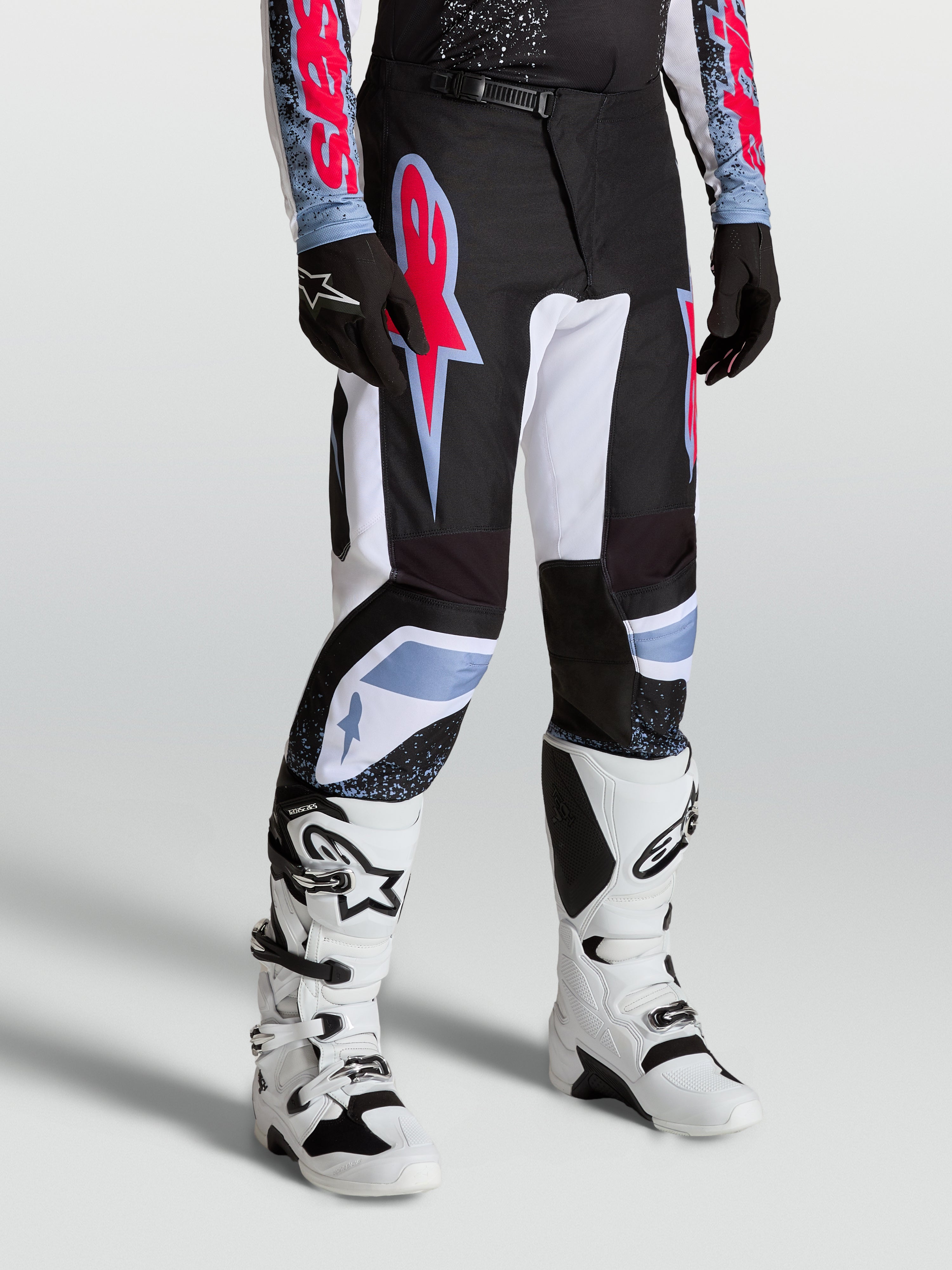 Pantalones Alpinestars Fluid Drag de motocross para hombre, negros y blancos con acentos rojos y azules, diseño ergonómico 3D.