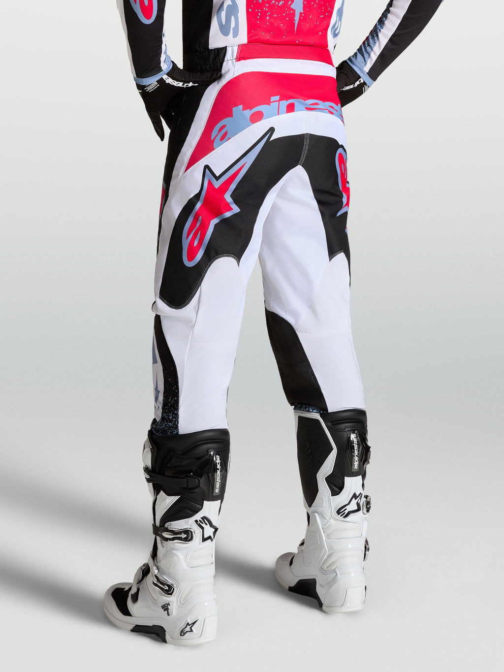 Alpinestars Pantalones Fluid Drag, pantalones de motocross para hombre, blancos y negros con detalles en rojo y azul claro, diseño ergonómico para pilotaje off-road, vista trasera.