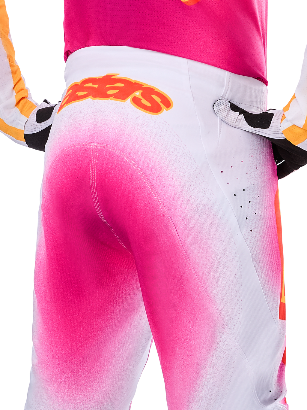 Alpinestars Limited Edition Supertech AFD MIG Pants, pantalones de motocross, rosa flúor y blanco con un efecto de degradado tipo pintura en aerosol, logotipo naranja grande de Alpinestars en la parte posterior de la cintura, vista de primer plano que muestra el ajuste atlético y las perforaciones de ventilación.