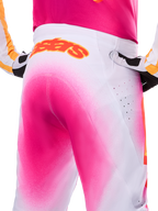 Alpinestars Limited Edition Supertech AFD MIG Pants, pantalones de motocross, rosa flúor y blanco con un efecto de degradado tipo pintura en aerosol, logotipo naranja grande de Alpinestars en la parte posterior de la cintura, vista de primer plano que muestra el ajuste atlético y las perforaciones de ventilación.