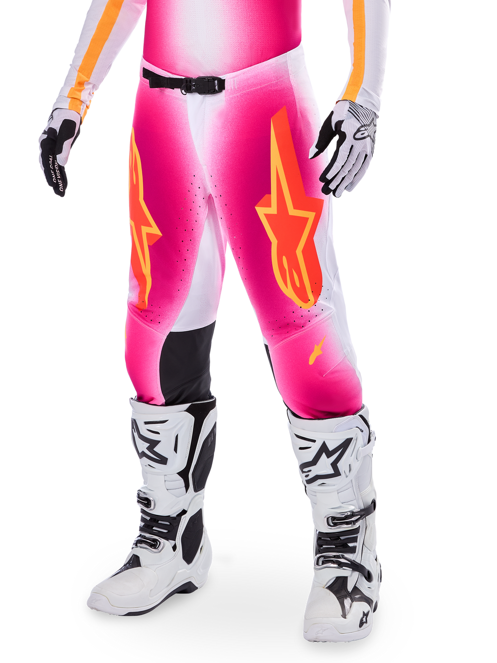 Alpinestars Supertech AFD MIG Limited Edition, pantalones de motocross rosas con logotipos de estrellas en naranja y amarillo, usados con botas de motocross blancas y guantes blancos y negros, con paneles internos negros en las rodillas y un ajuste atlético, parte de un conjunto de equipamiento de alto rendimiento