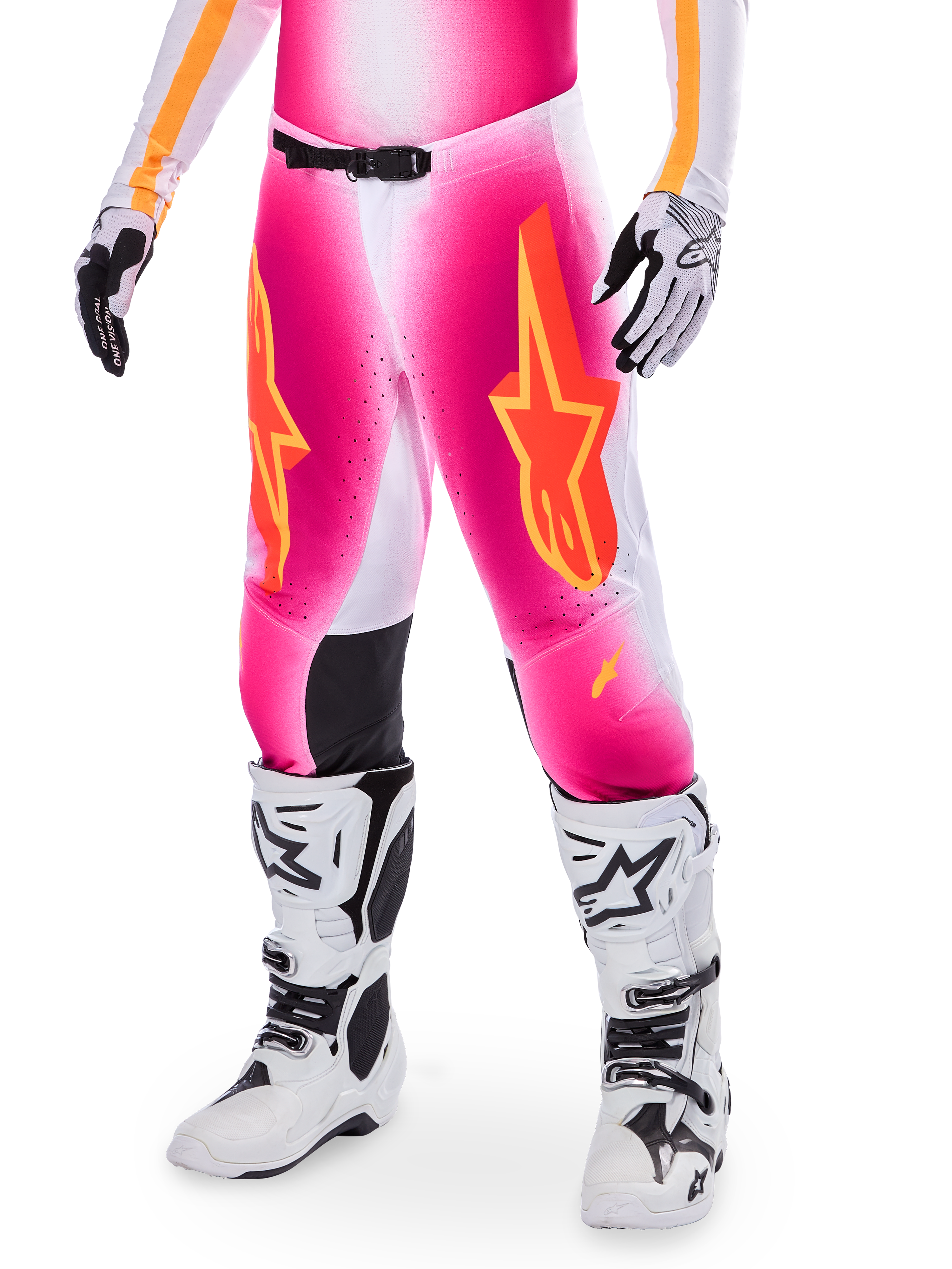 Alpinestars Supertech AFD MIG Limited Edition, pantalones de motocross rosas con logotipos de estrellas en naranja y amarillo, usados con botas de motocross blancas y guantes blancos y negros, con paneles internos negros en las rodillas y un ajuste atlético, parte de un conjunto de equipamiento de alto rendimiento