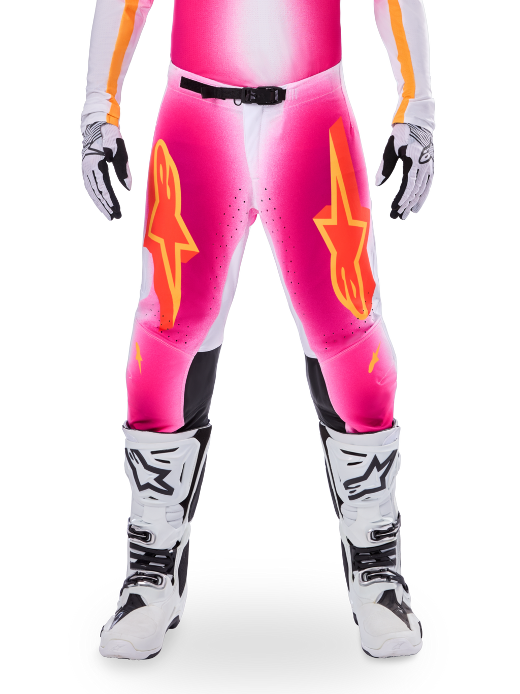Alpinestars Limited Edition Supertech AFD MIG Pants, pantalones de motocross para carreras, rosa flúor y blanco con detalles en naranja, con grandes logotipos de estrellas en los muslos, paneles perforados y zonas de agarre negras en las rodillas, usados con botas de motocross blancas y negras