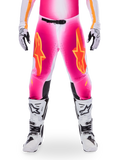 Alpinestars Limited Edition Supertech AFD MIG Pants, pantalones de motocross para carreras, rosa flúor y blanco con detalles en naranja, con grandes logotipos de estrellas en los muslos, paneles perforados y zonas de agarre negras en las rodillas, usados con botas de motocross blancas y negras