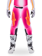 Alpinestars Limited Edition Supertech AFD MIG Pants, pantalones de motocross para carreras, rosa flúor y blanco con detalles en naranja, con grandes logotipos de estrellas en los muslos, paneles perforados y zonas de agarre negras en las rodillas, usados con botas de motocross blancas y negras